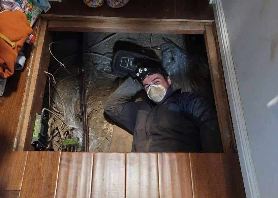 Modern Air technician working in a crawlspace with a headlamp
