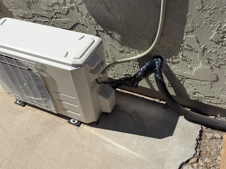 Bosch ductless outdoor unit on a concrete slab with an insulated refrigerant line running along a stucco wall, Morgan Hill, CA