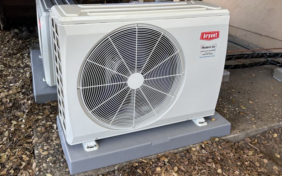Bryant heat pump installed on a concrete pad beside a home