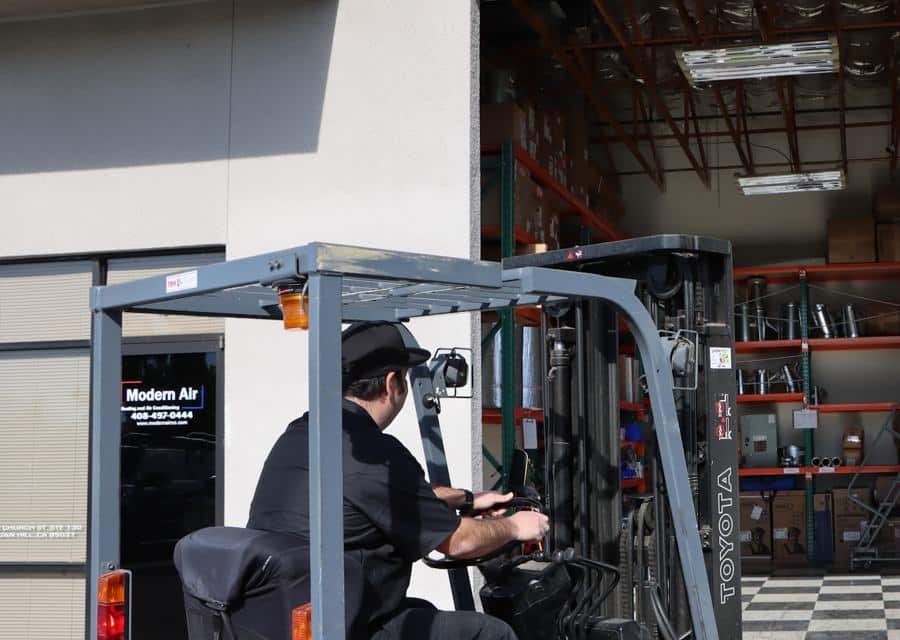 Technician moving equipment with a forklift in the Modern Air warehouse