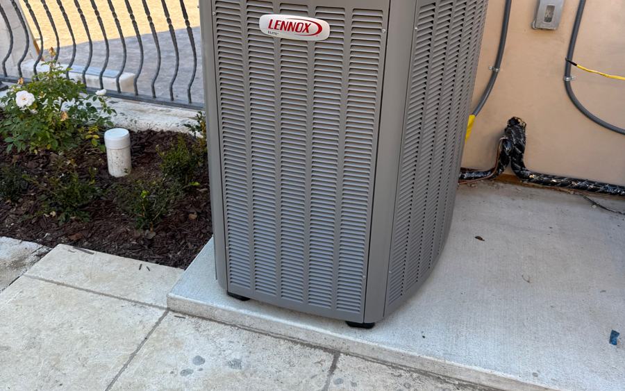 New air conditioner condenser installed beside flowering shrubs