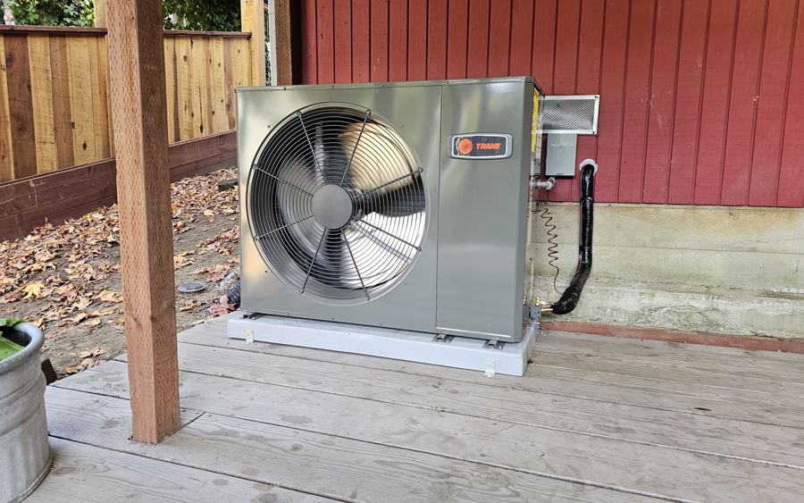 Trane low-profile heat pump installed beside a wooden deck